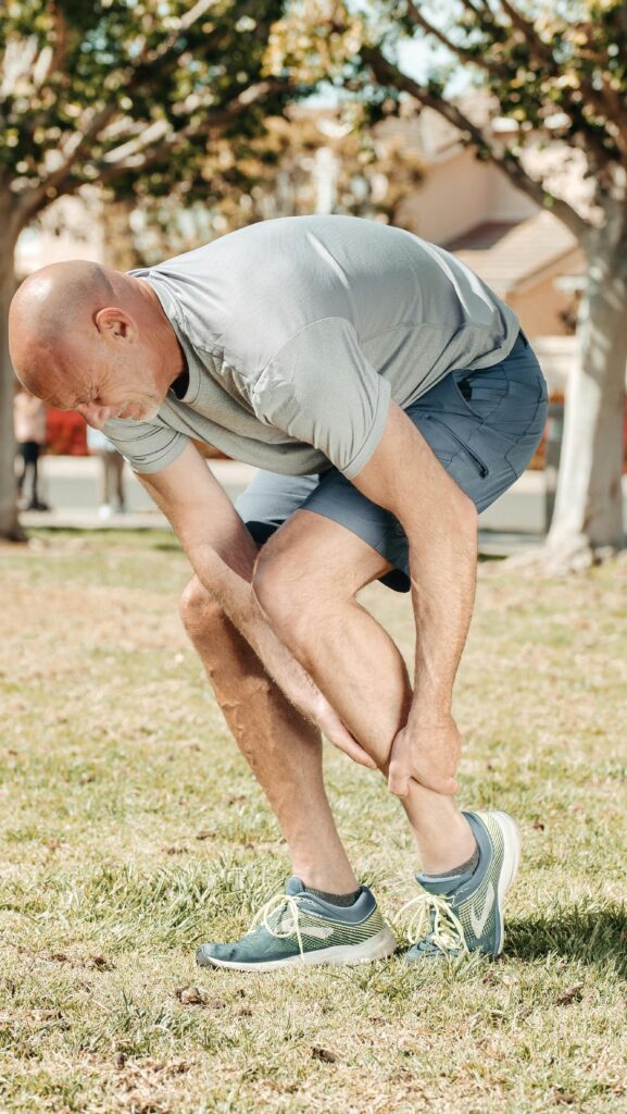 Person stretching leg outdoors in sunlight.